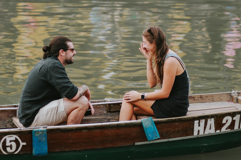 a man and a woman sitting in a boat on the water