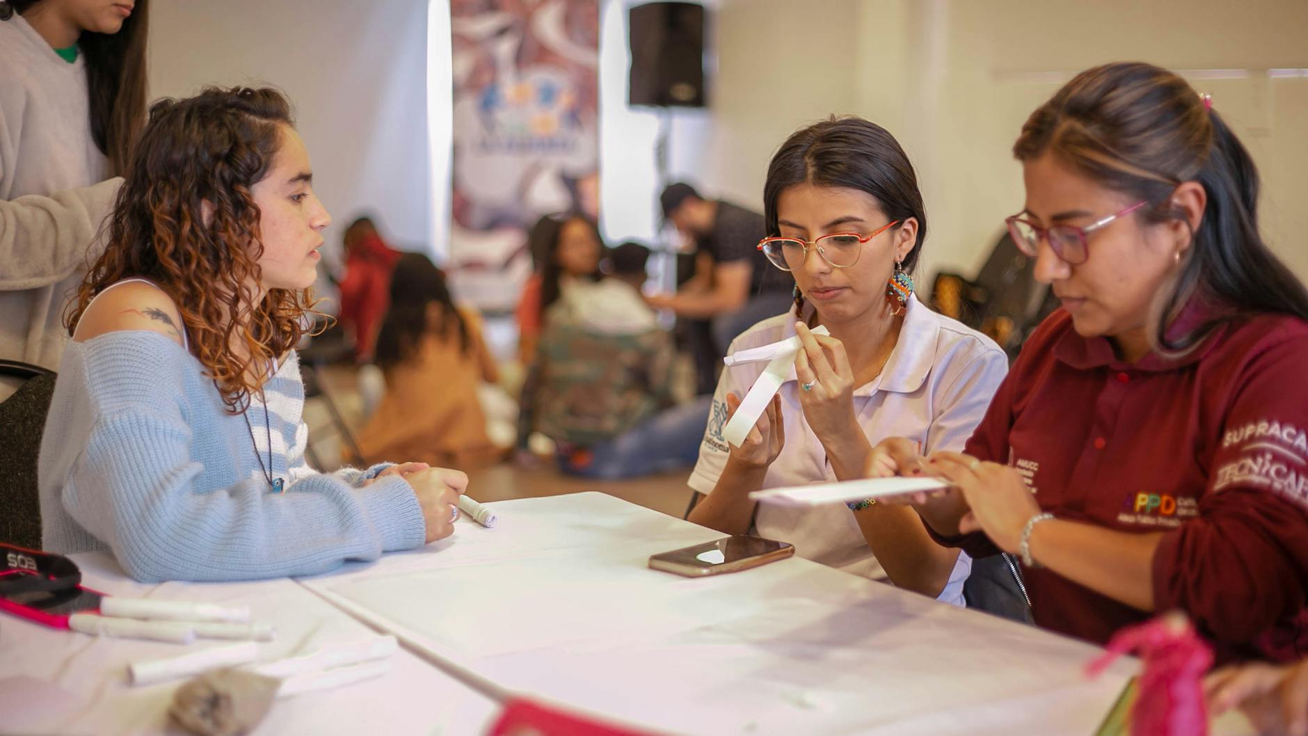 Group of women creating paper crafts in a hands-on workshop setting, fostering creativity.