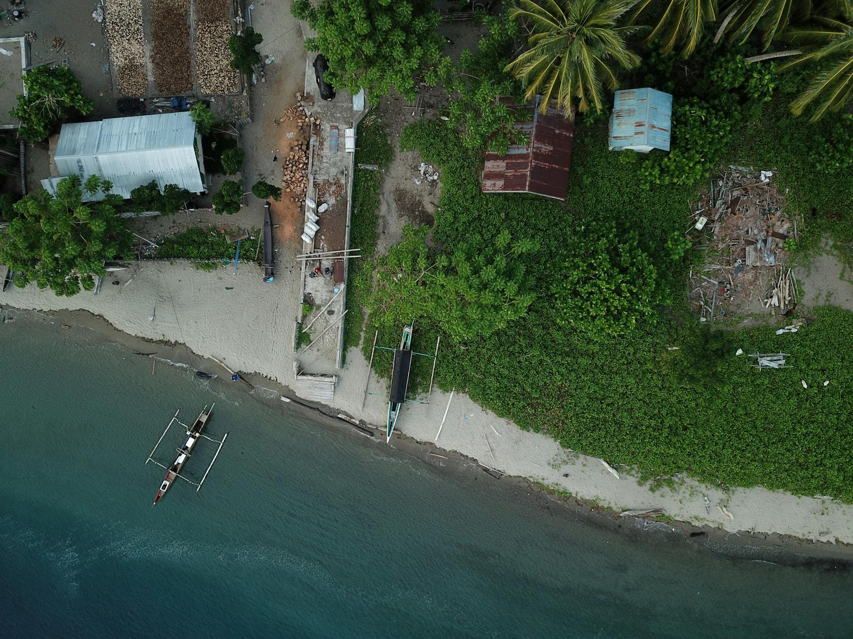 Drone shot capturing a coastal scene with boats and greenery in Una-Una, Indonesia.