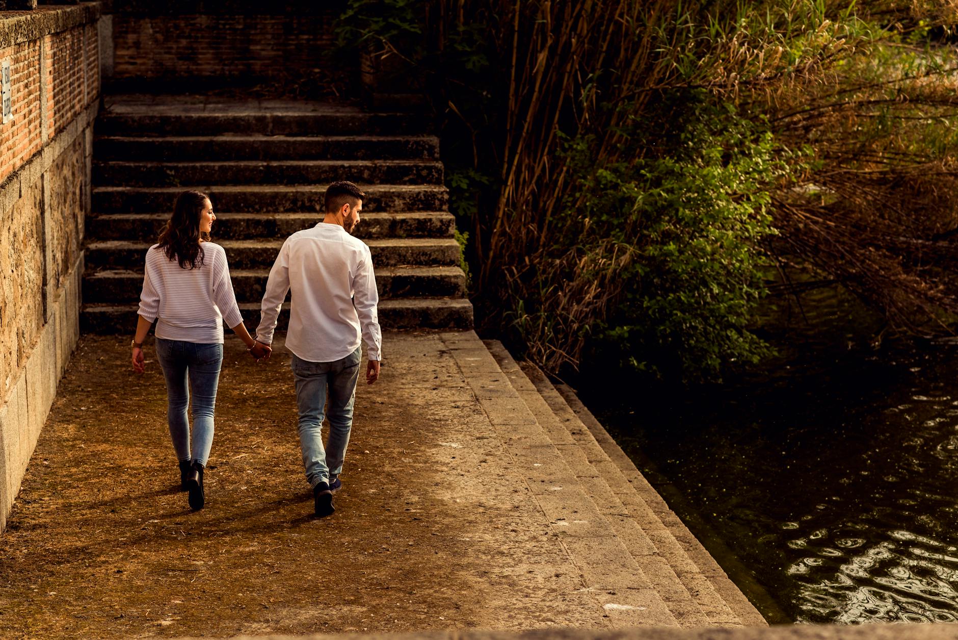 A couple walking hand in hand beside a canal in Toledo, Spain, fostering romance and tranquility.