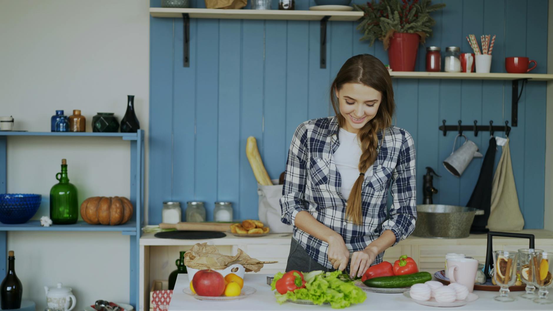 Smiling woman chopping vegetables in a cozy kitchen setting.