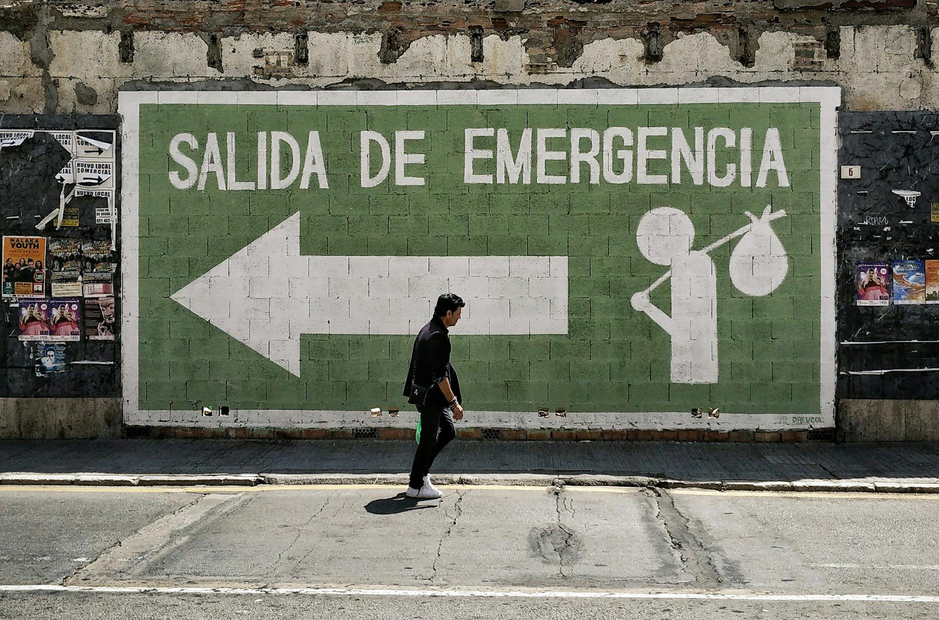 A man walks by an emergency exit graffiti mural on a street in Málaga, Spain.